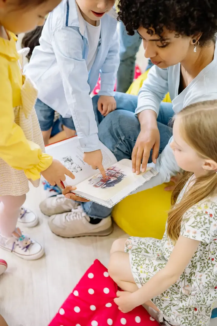 Children gathered around a teacher looking at a picture book